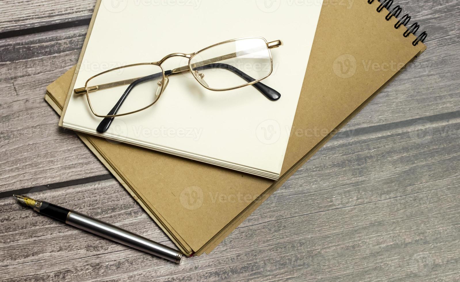 bloc-notes, stylo et lunettes sur un bureau en bois. notion d'entreprise photo