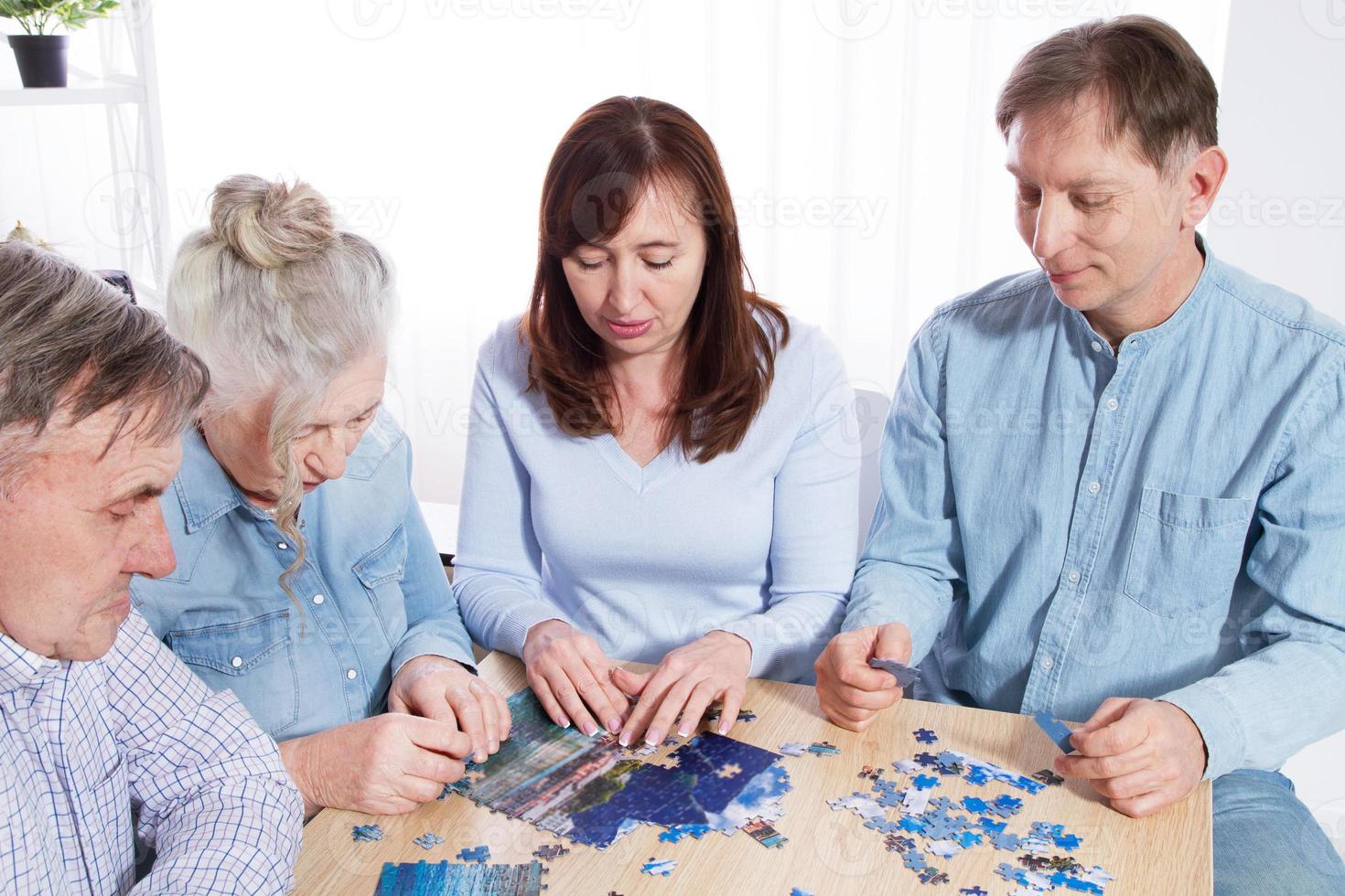 la famille rassemble un puzzle à table à la maison photo