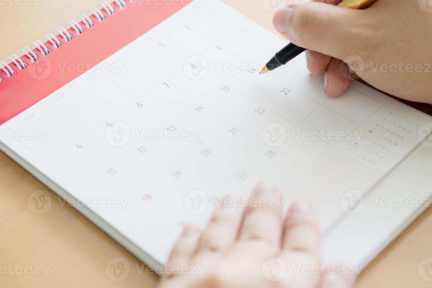 main tenant un stylo et un marquage sur le calendrier photo
