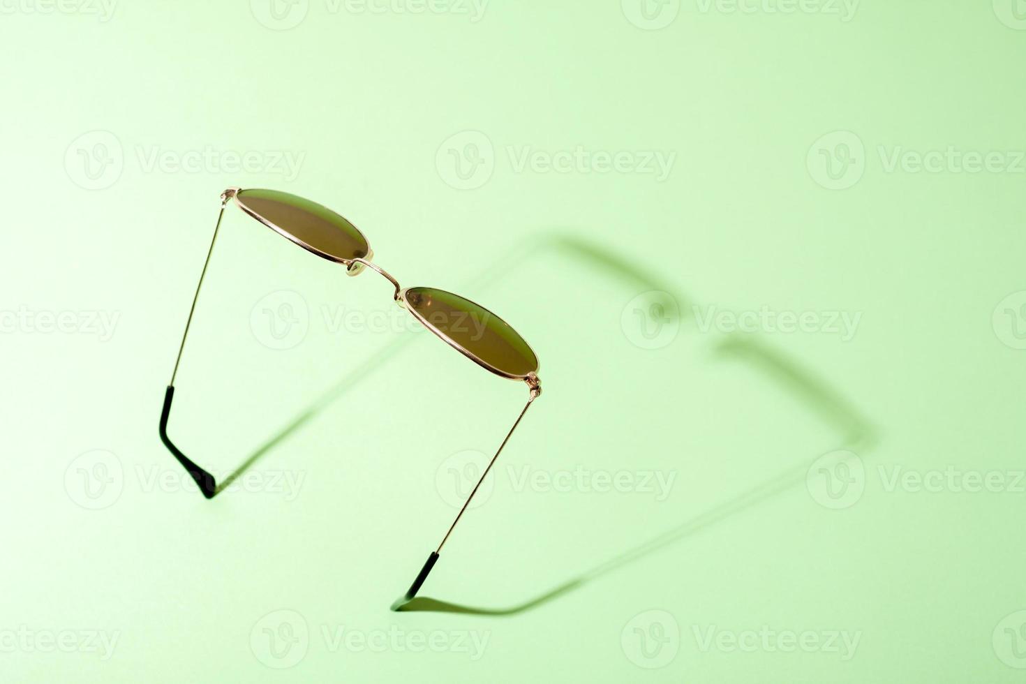 image minimaliste de lunettes de soleil avec ombre sur fond vert. photo