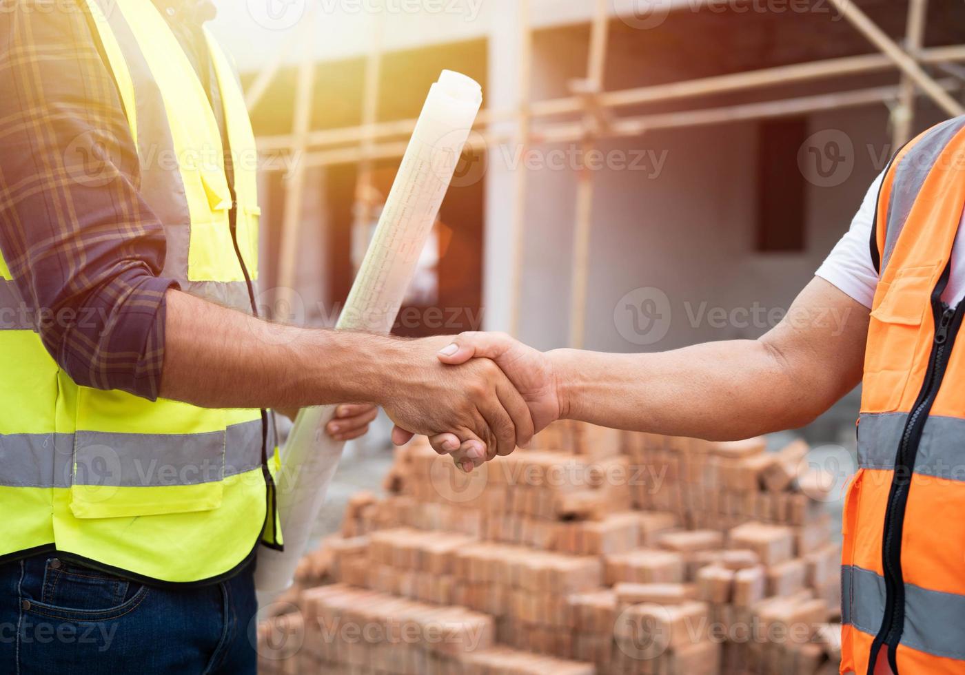 gros plan sur une poignée de main, un ingénieur civil masculin professionnel ou un architecte avec un entrepreneur, un contremaître. succès, tout en rencontrant le projet de construction et en pointant avec une poignée de main sur le chantier de construction. photo