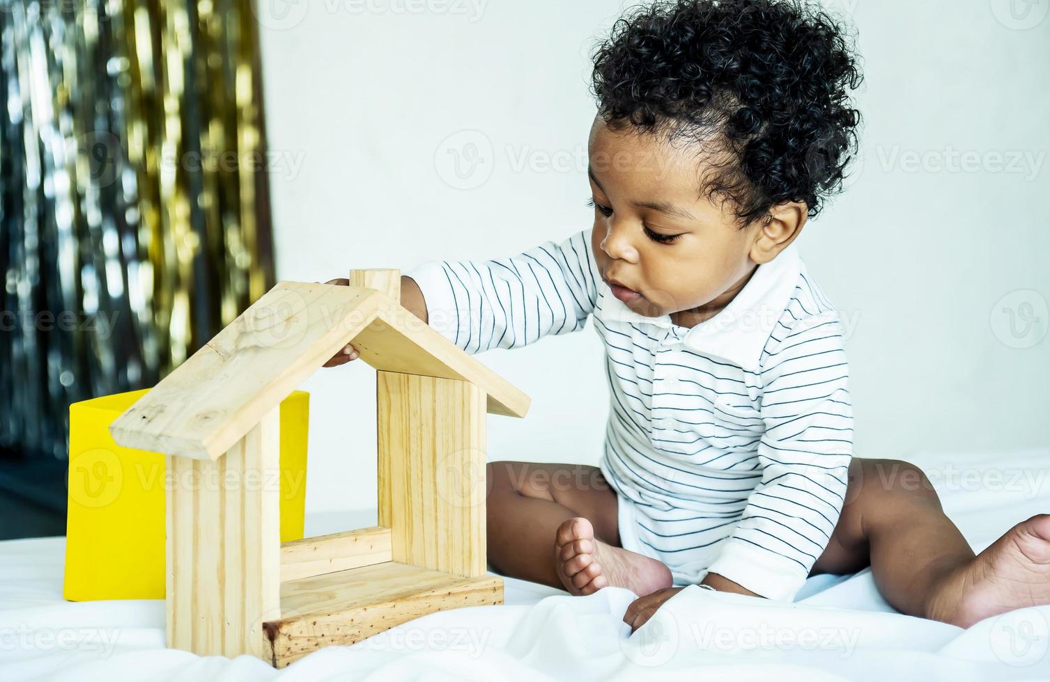 mignon petit garçon afro-américain jouant avec un jouet de maison en bois, il se sent heureux. photo
