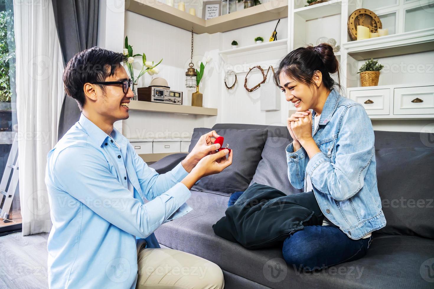 quel beau cadeau beau jeune homme assis sur le canapé et tenant une boîte  cadeau tandis que sa petite amie se tient derrière lui et sourit 13550148  Photo de stock chez Vecteezy