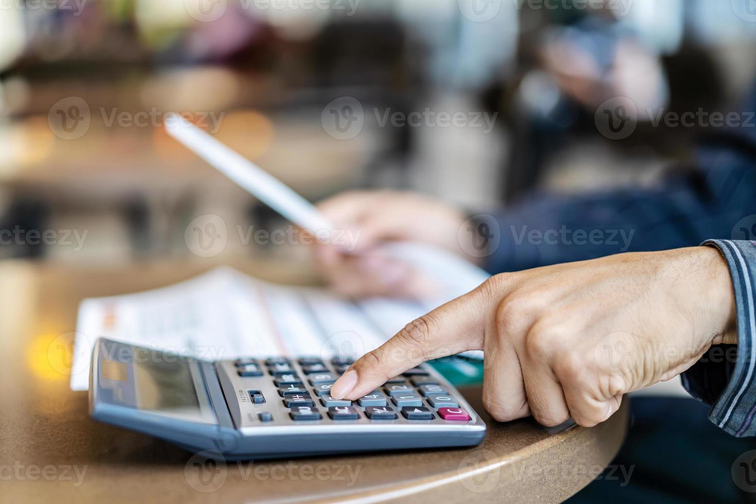 les hommes d'affaires comptables appuient sur la calculatrice pour calculer les différents coûts qui doivent être payés par la facture, de nombreuses factures détenues et placées sur la table, le concept des systèmes financiers et fiscaux. photo