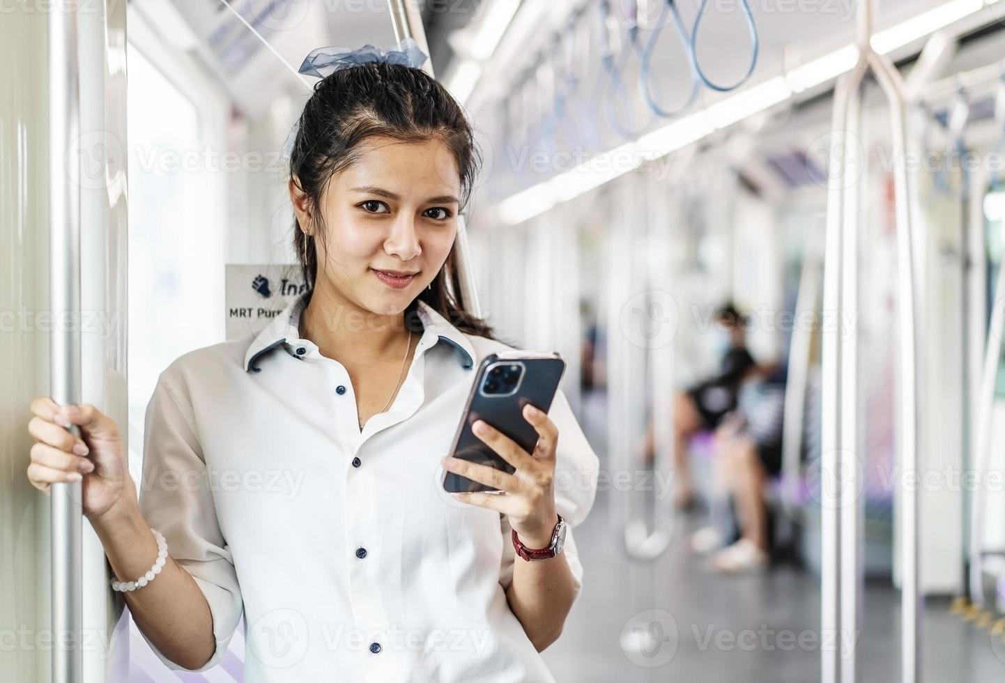 jeune femme asiatique passagère debout et utilisant un téléphone portable à l'intérieur d'une voiture vide de métro ou de train aérien, loisirs et vie quotidienne photo