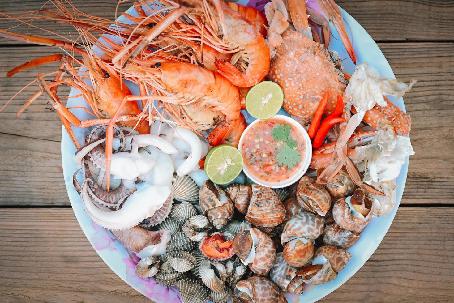 Assiette de fruits de mer avec crevettes coquillages crabe calmar coque babylone tachetée avec sauce aux fruits de mer chili citron citron vert servir sur la table à manger, crevettes crevettes menu buffet de fruits de mer plats cuisinés photo