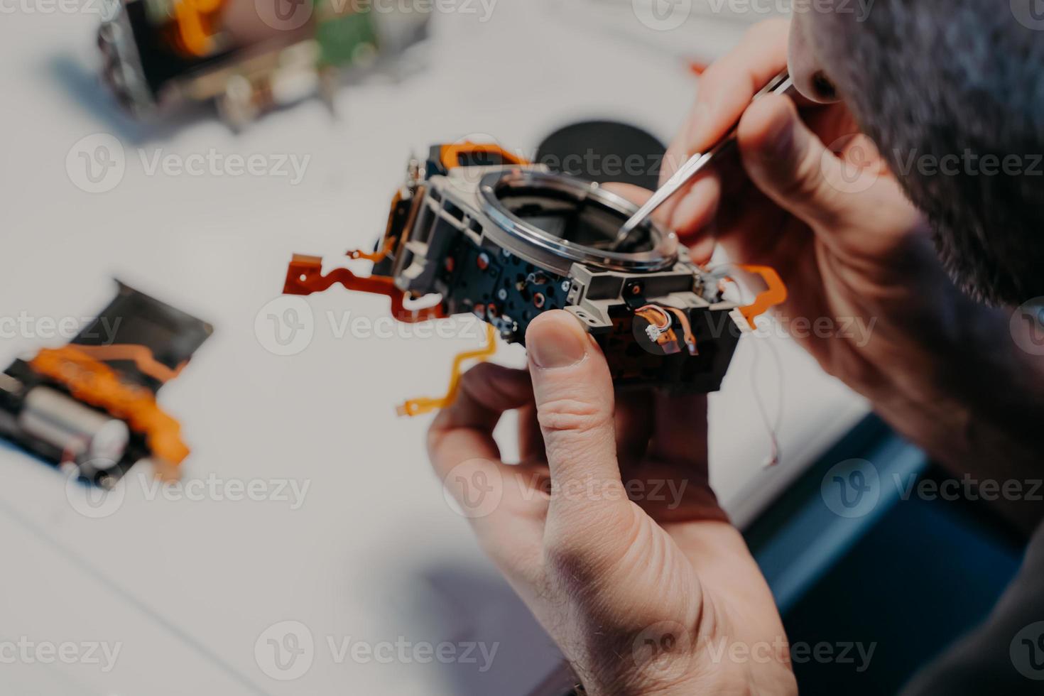 processus de réparation. un technicien professionnel répare un appareil photo numérique cassé, pose dans un centre de service ou un atelier, utilise un outil spécial. entretien et assistance