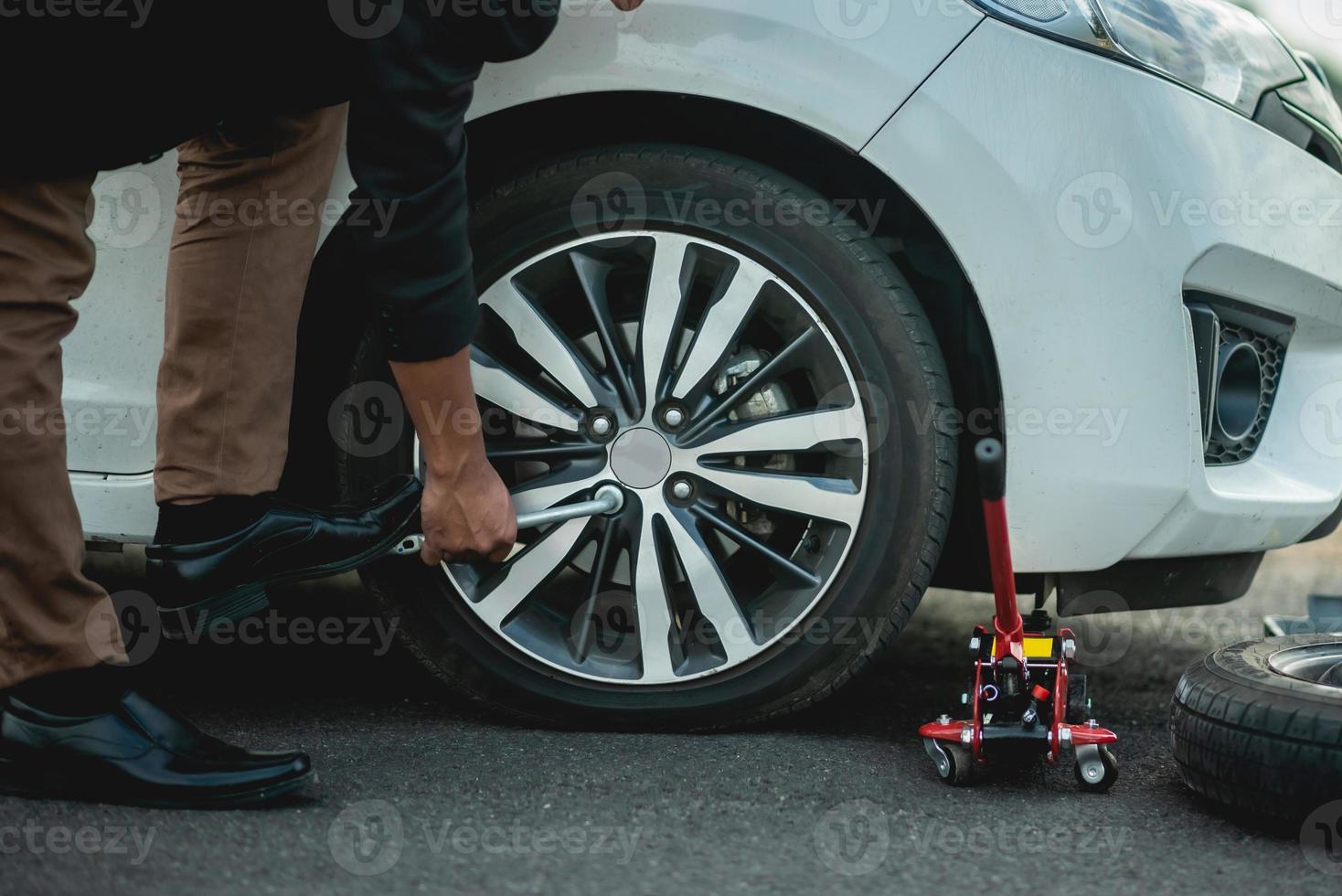 les gens d'affaires changent les roues arrière, les pneus qui fuient sur le bord de la route en se rendant au travail photo