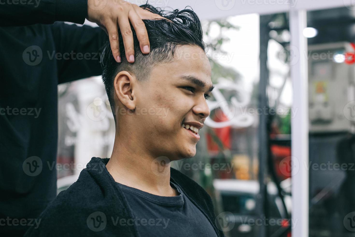 jeune homme visitant un salon de coiffure. coiffeur massant la tête du consommateur. soins personnels, beauté masculine. coiffeur. photo