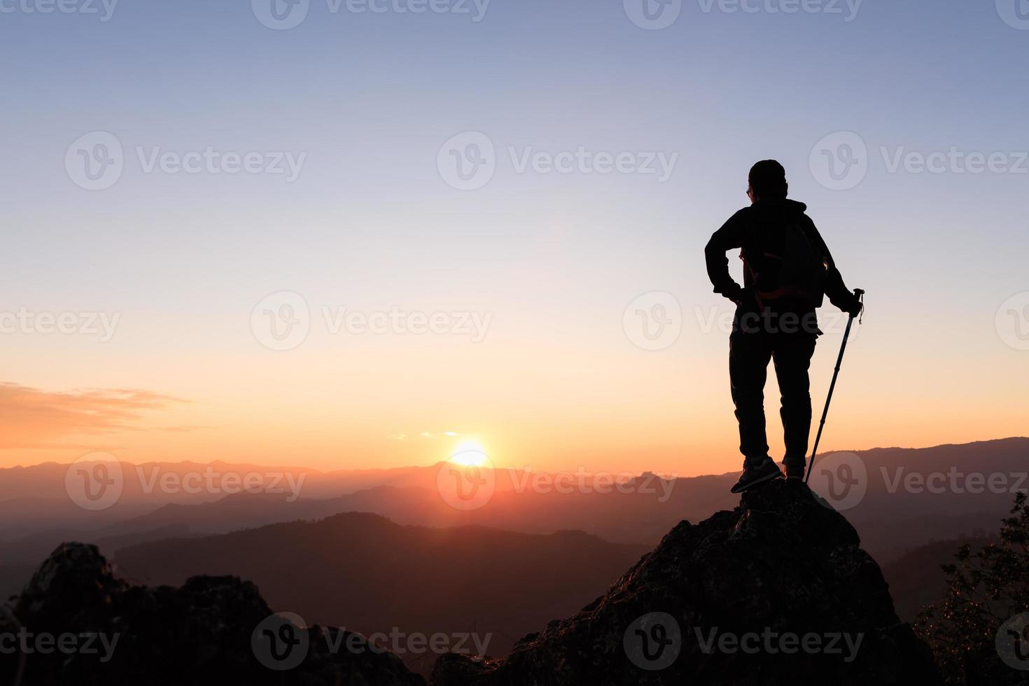 silhouette de randonneur debout au sommet de la colline et profitant du lever du soleil sur la vallée. concept d'ambition et de réussite photo