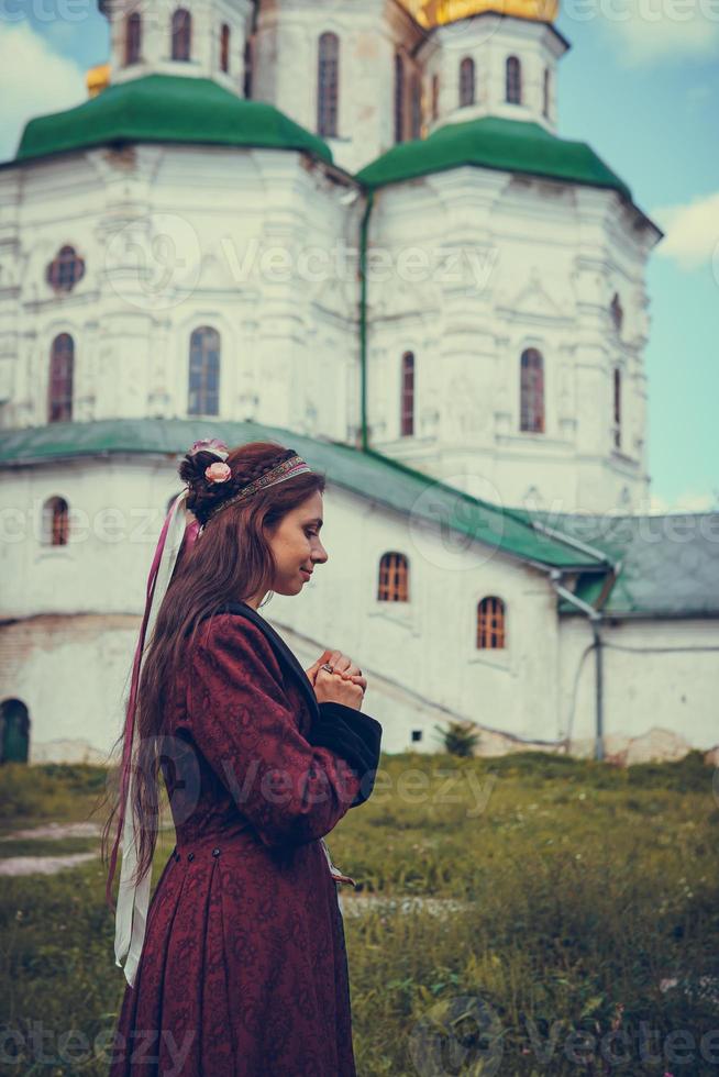 portrait d'une femme brune en prière, vêtue de vêtements baroques historiques, à l'extérieur photo