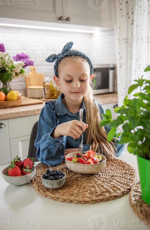 jolie petite fille mange une salade de fruits photo