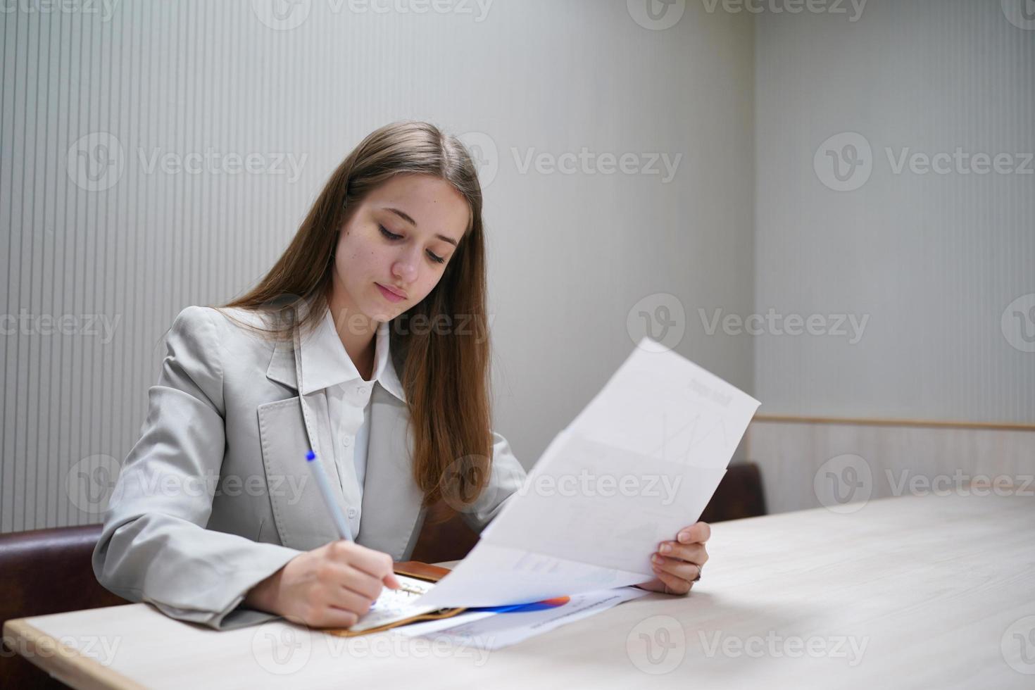 jeune femme d'affaires sur le lieu de travail et lisant du papier au bureau photo