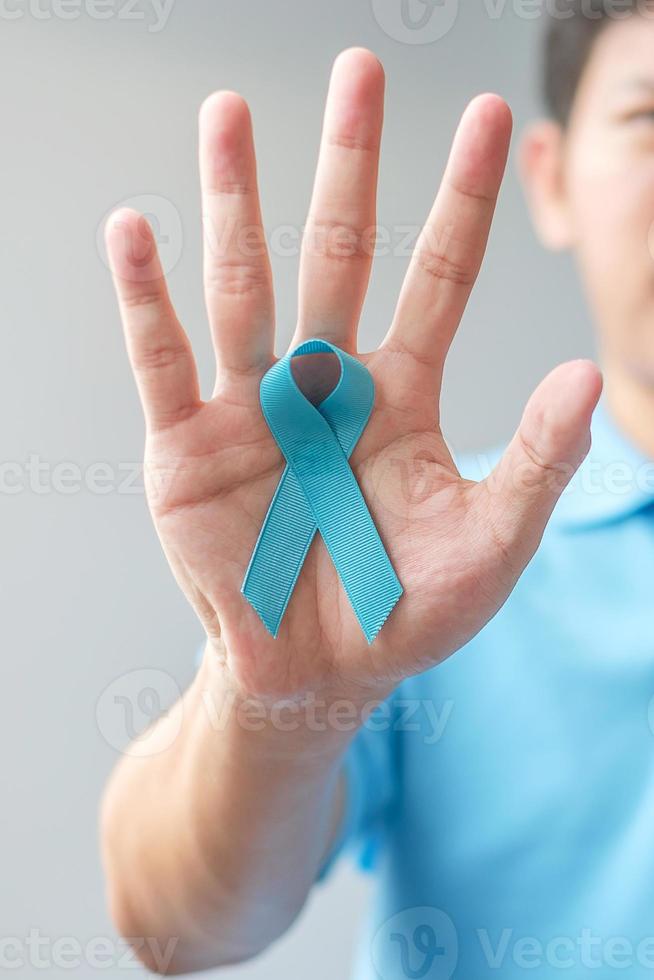 novembre mois de sensibilisation au cancer de la prostate, homme en chemise bleue avec la main tenant un ruban bleu pour soutenir les personnes vivant et malades. soins de santé, hommes internationaux, père et concept de la journée mondiale du cancer photo