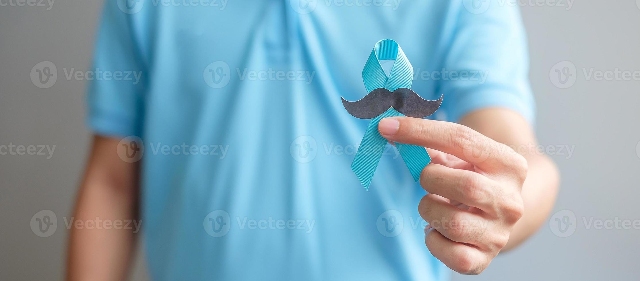 novembre mois de sensibilisation au cancer de la prostate, homme tenant un ruban bleu avec moustache pour soutenir les personnes vivant et malades. soins de santé, hommes internationaux, père et concept de la journée mondiale du cancer photo