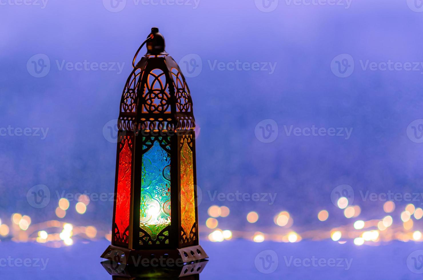 mise au point sélective sur le verre de couleur bleue de la lanterne avec des lumières décorant pour le nouvel an islamique mis au fond de la fenêtre avec bokeh de goutte de pluie. photo
