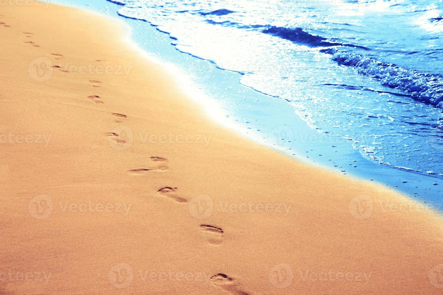 marchant sur la plage, laissant des empreintes de pas dans le sable. photo