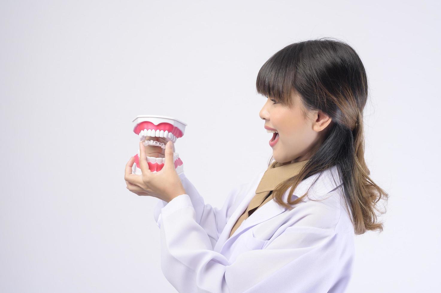 jeune femme dentiste souriant sur fond blanc studio photo