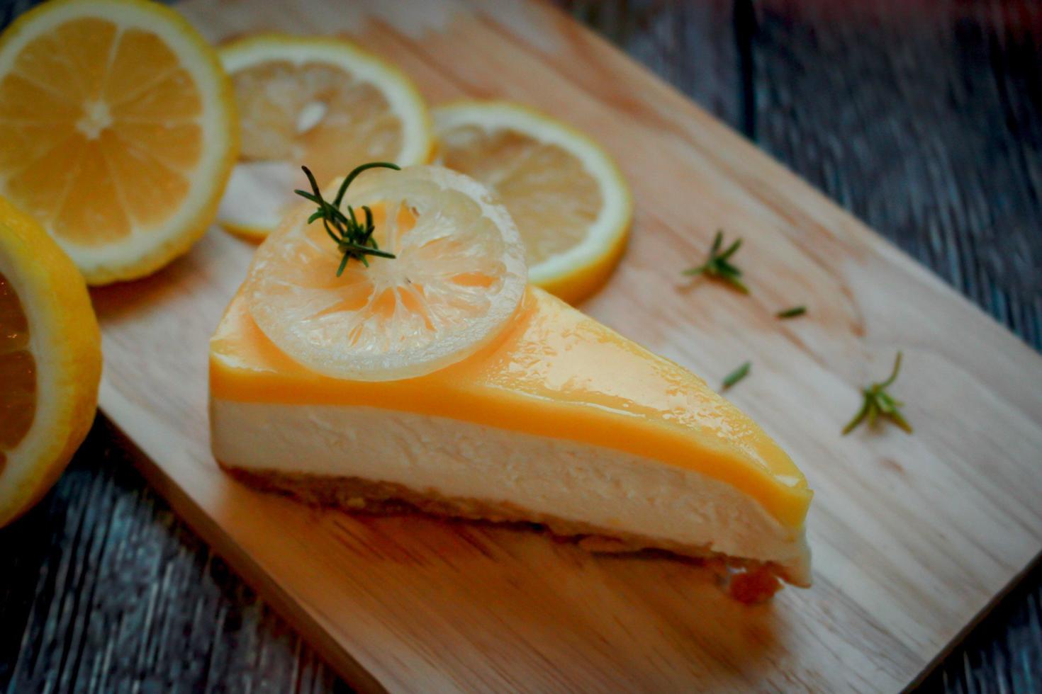 un morceau de tarte au fromage à la crème au citron avec des tranches de citron jaune frais sur une planche à découper en bois de cuisine photo