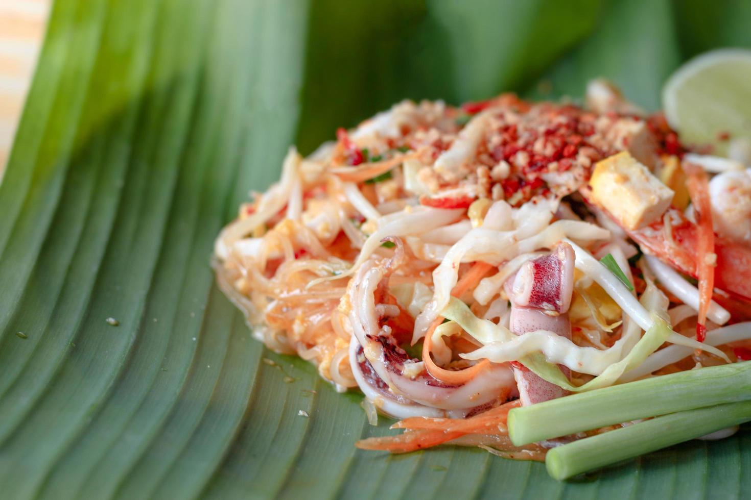 délicieux fruits de mer pad thai nouilles de riz sautées sur feuille de banane verte, l'un des plats de rue thaïlandais préférés les plus populaires. photo