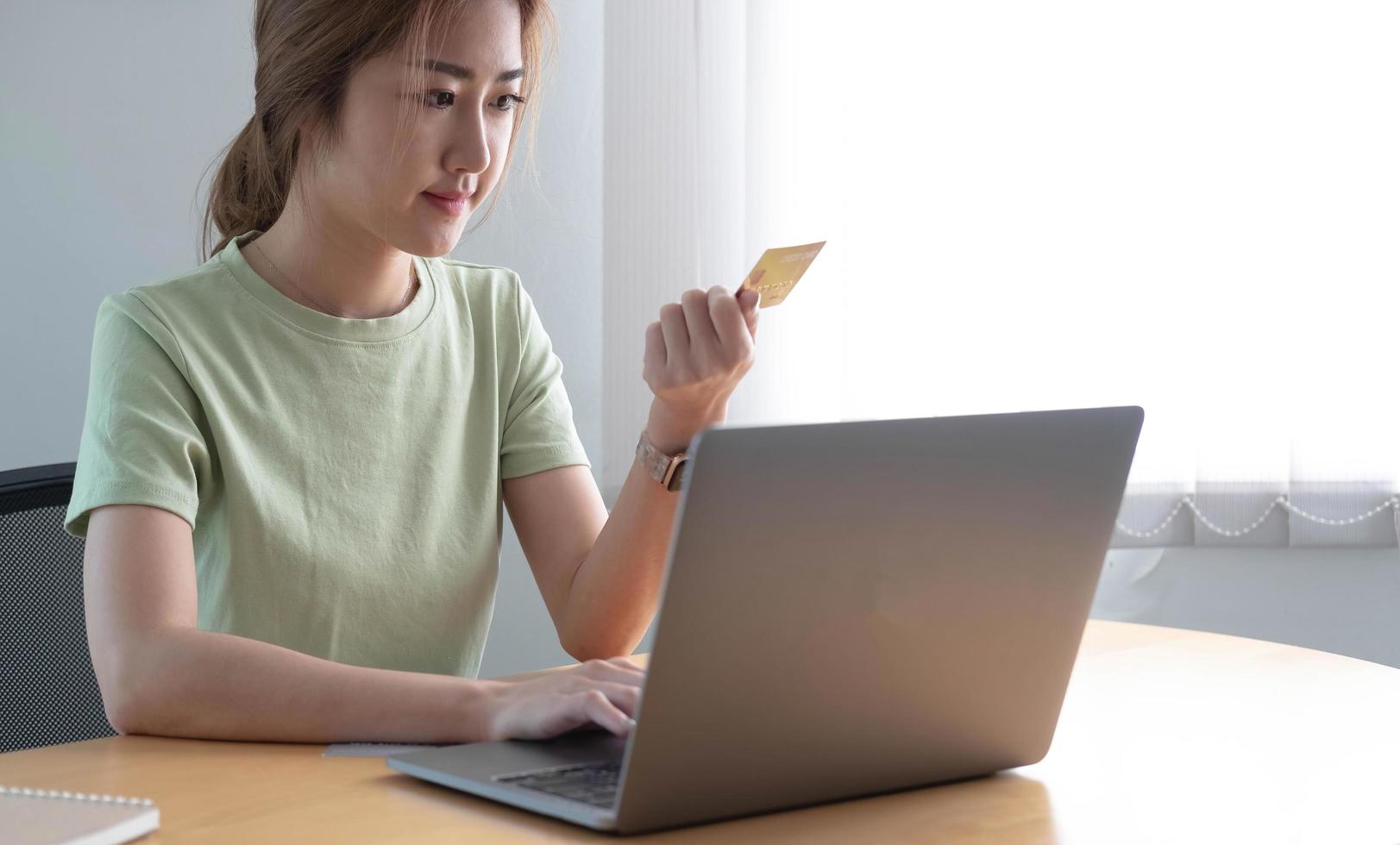 paiement en ligne woman's hands holding a credit card and using laptop computer for online shopping photo