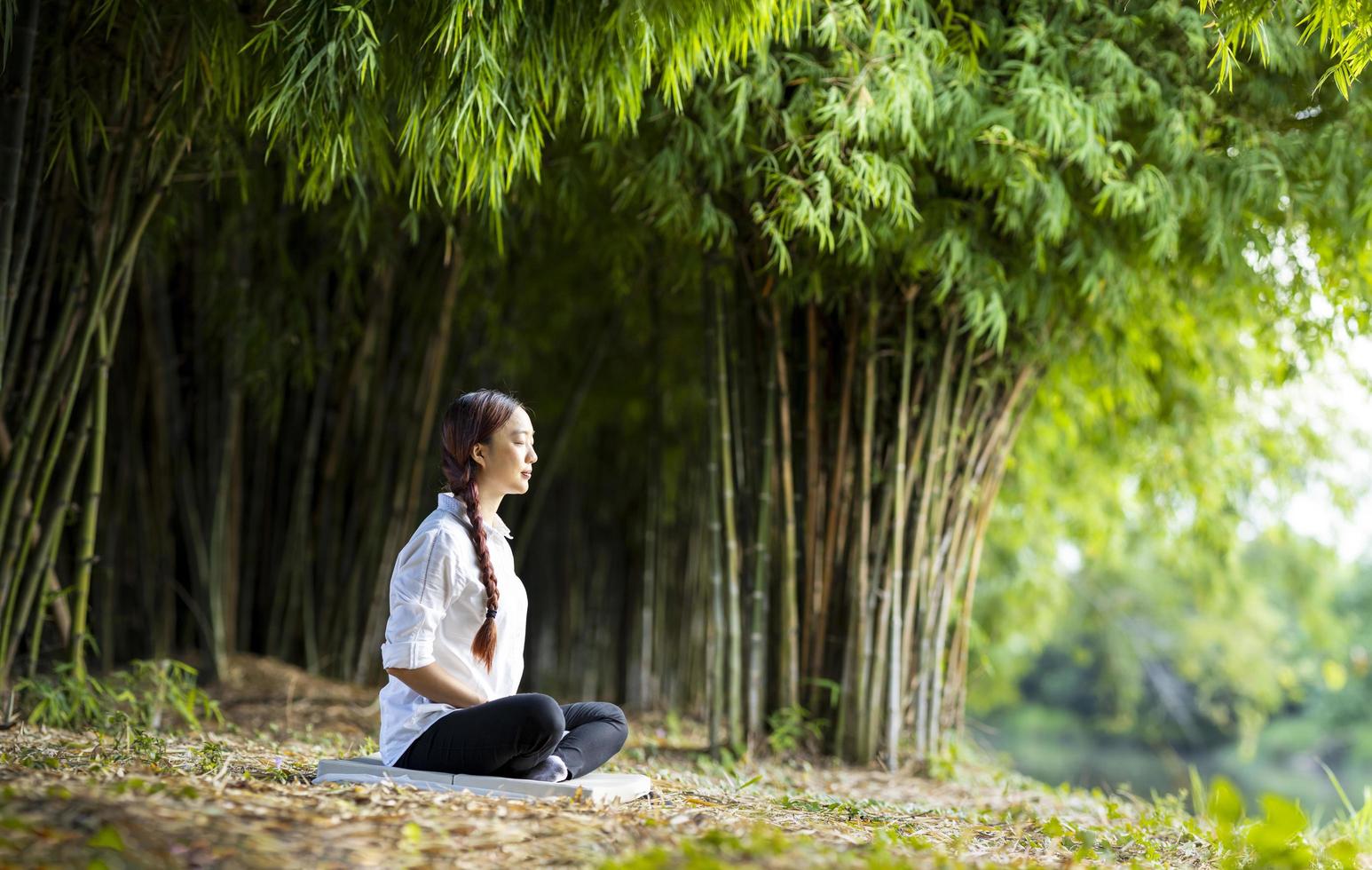 femme pratiquant la méditation de manière relaxante dans la forêt de bambous pour atteindre le bonheur de la sagesse de la paix intérieure pour un concept sain d'esprit et d'âme photo