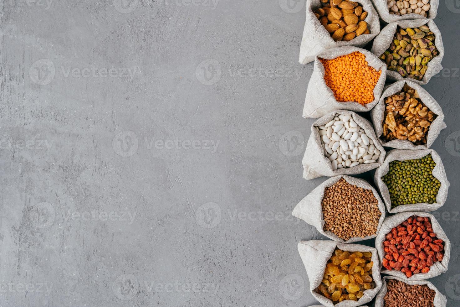sacs avec des produits sains nutritifs dans de petits sacs debout dans la rangée isolés sur fond de texture grise avec copie vierge de l'espace pour le texte photo