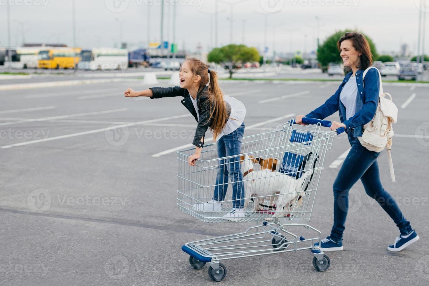 photo d'une petite fille heureuse avec sa mère et ses animaux de compagnie dans un chariot, faire du shopping pendant le week-end, profiter du temps libre, rentrer à la maison avec de nouveaux achats. concept de famille, de loisirs, d'animaux et d'achat
