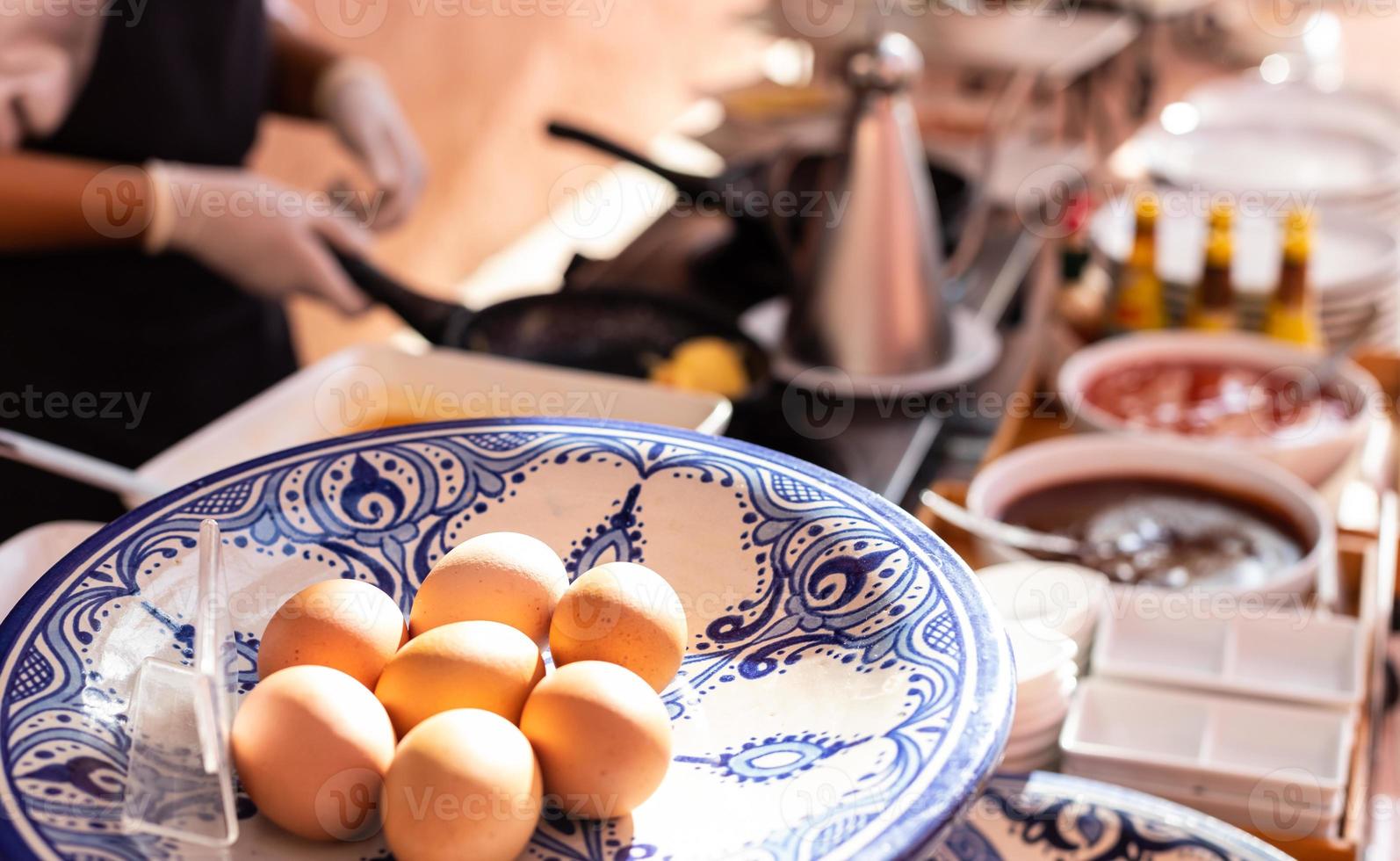 des œufs préparés en gros plan font des omelettes pour le petit-déjeuner avec un chef flou qui cuisine à l'arrière. photo