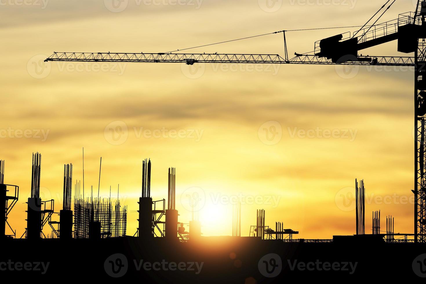 chantier de construction silhouette avec une grue sur fond jaune et le coucher du soleil brille à travers le soir photo