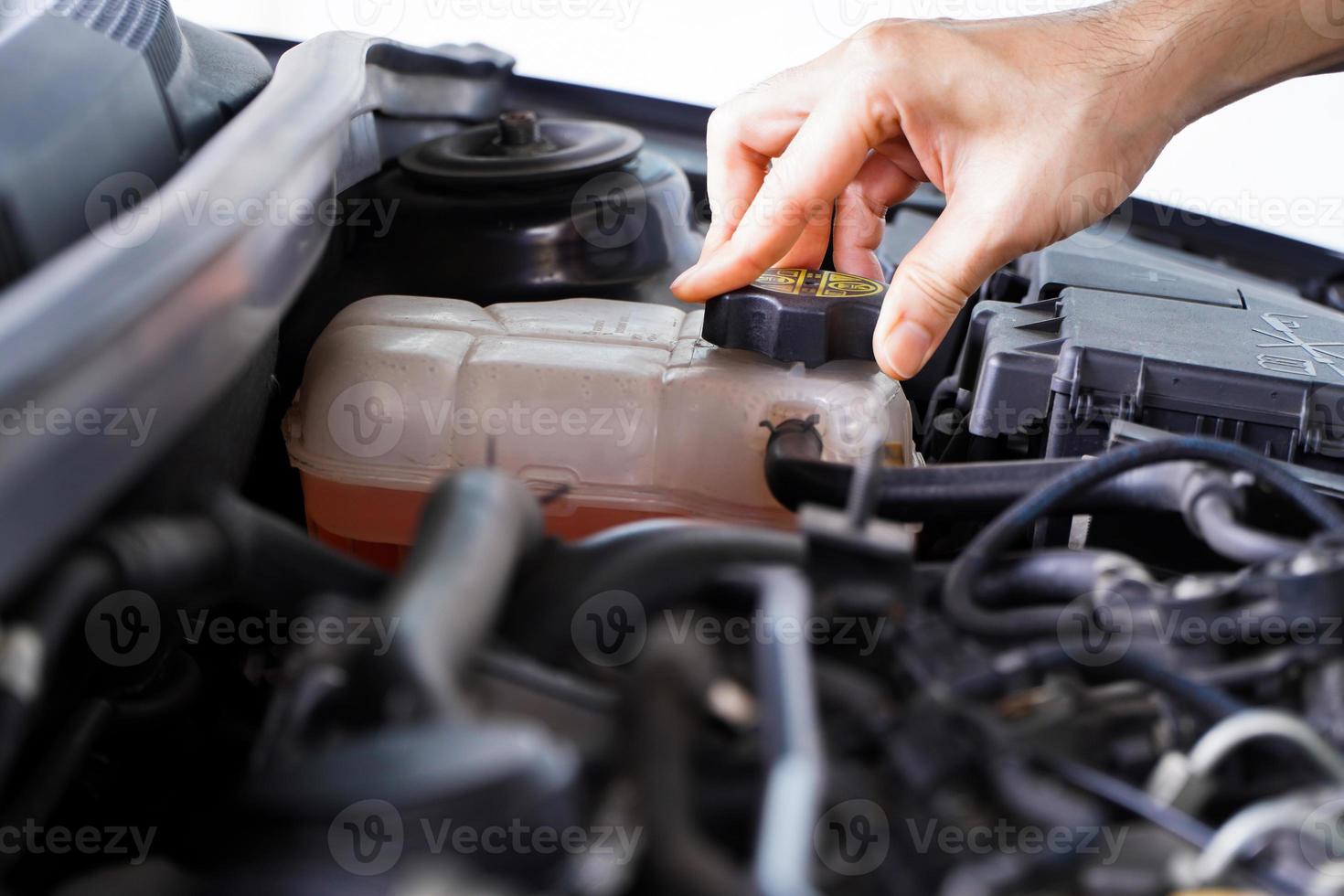 le mécanicien inspecte le vase d'expansion avec de l'antigel rose. niveau de liquide de refroidissement du véhicule dans le système de radiateur de la voiture. pièces automobiles photo