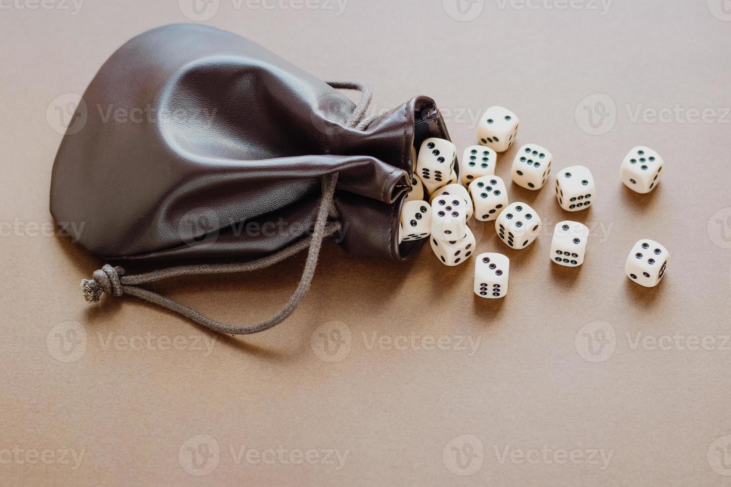 ensemble de dés de jeu sortis d'un sac en cuir sur fond marron. concept avec espace de copie pour les jeux, le plateau de jeu, le jeu de rôle, le dnd, le risque, la chance, la bonne chance ou le jeu. vue de dessus d'image tonique photo