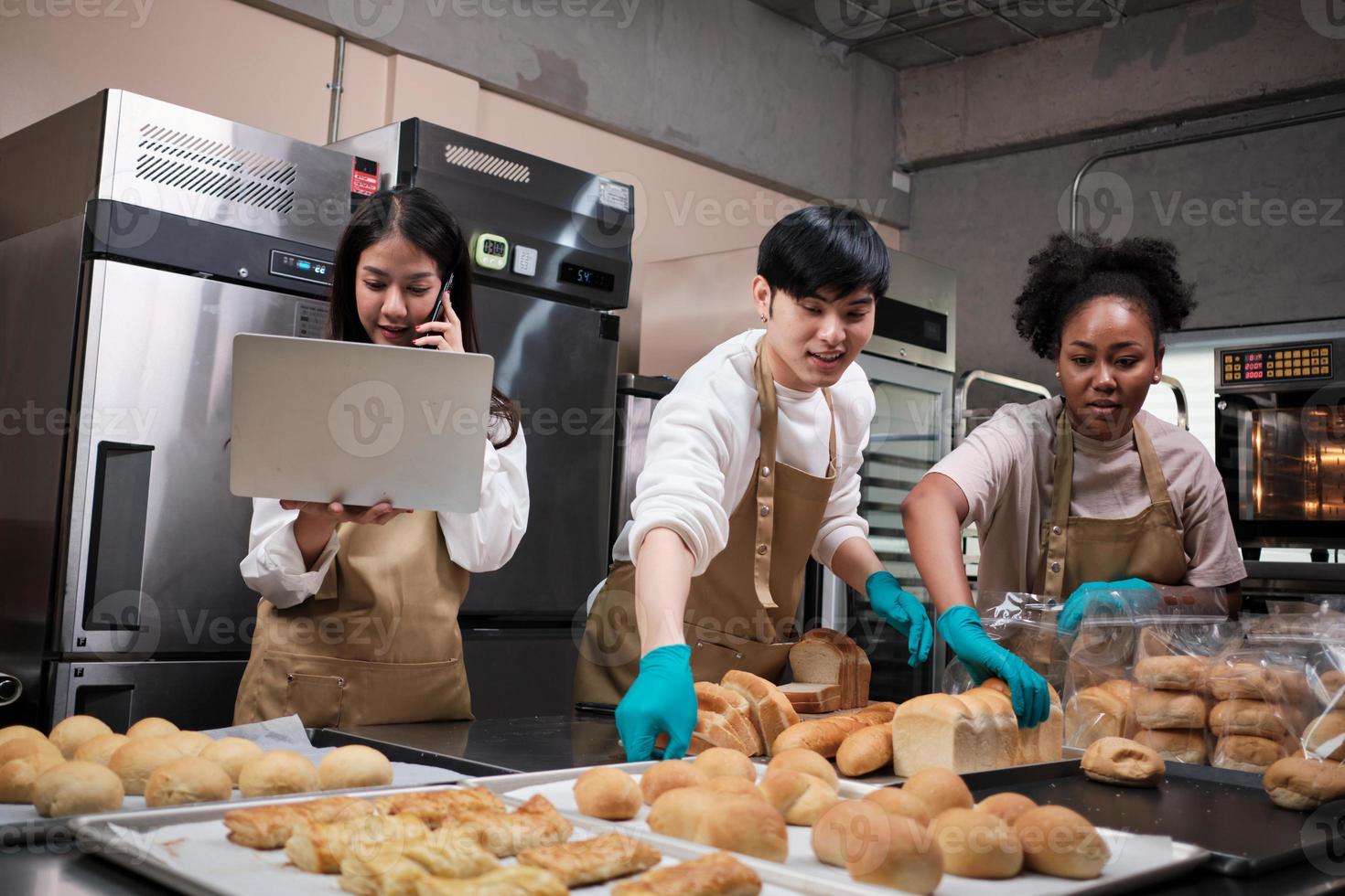 trois jeunes amis et partenaires de démarrage de pâte à pain et de pâtisseries occupés à faire des pâtisseries maison tout en cuisinant des commandes en ligne, en emballant et en livrant dans une boulangerie, un petit entrepreneur photo