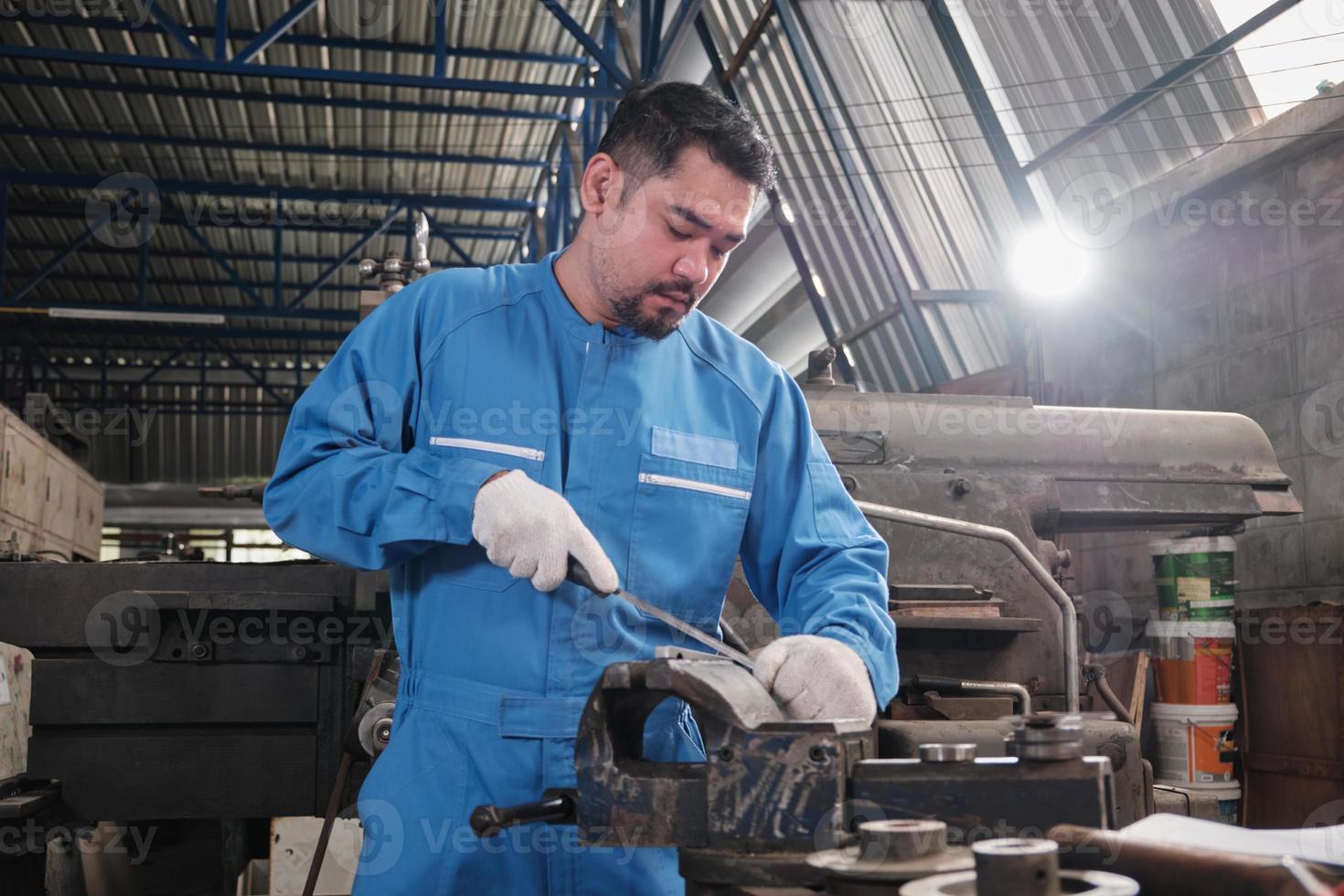 un ingénieur professionnel asiatique de l'industrie travaille dans un uniforme de sécurité avec des outils de précision pour la métallurgie, des tours mécaniques et un atelier de pièces de rechange dans l'usine de fabrication d'acier. photo