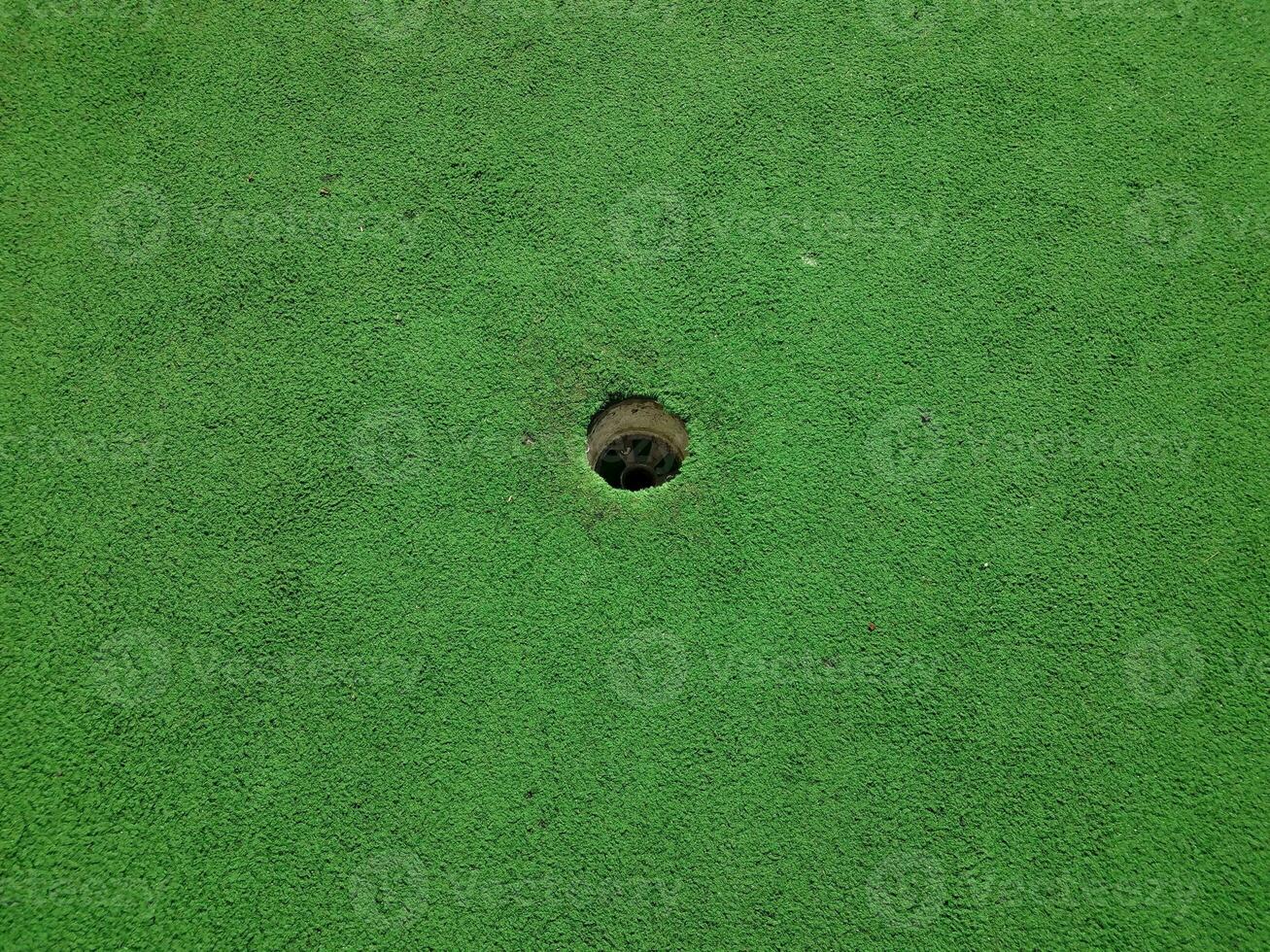 trou sur un parcours de golf miniature avec gazon artificiel vert photo