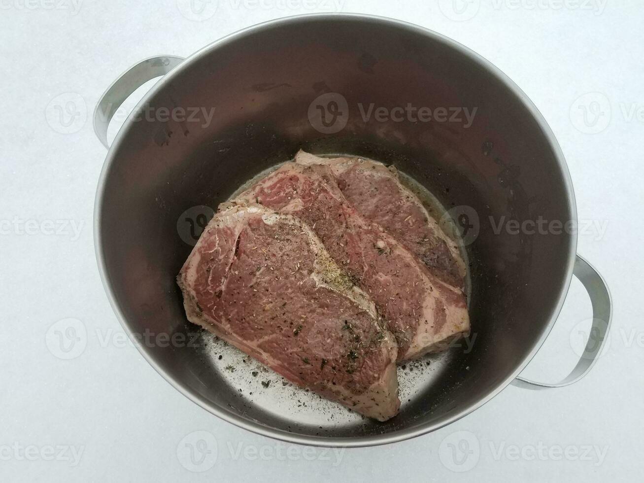 steak de boeuf avec assaisonnement et liquide dans une marmite en métal sur la neige photo