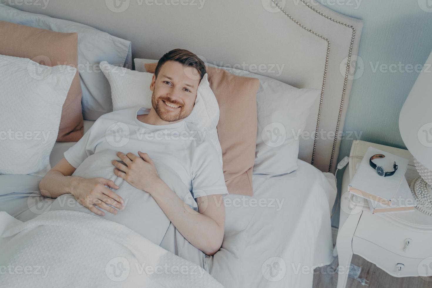 jeune homme bien reposé se réveillant le matin à la maison photo