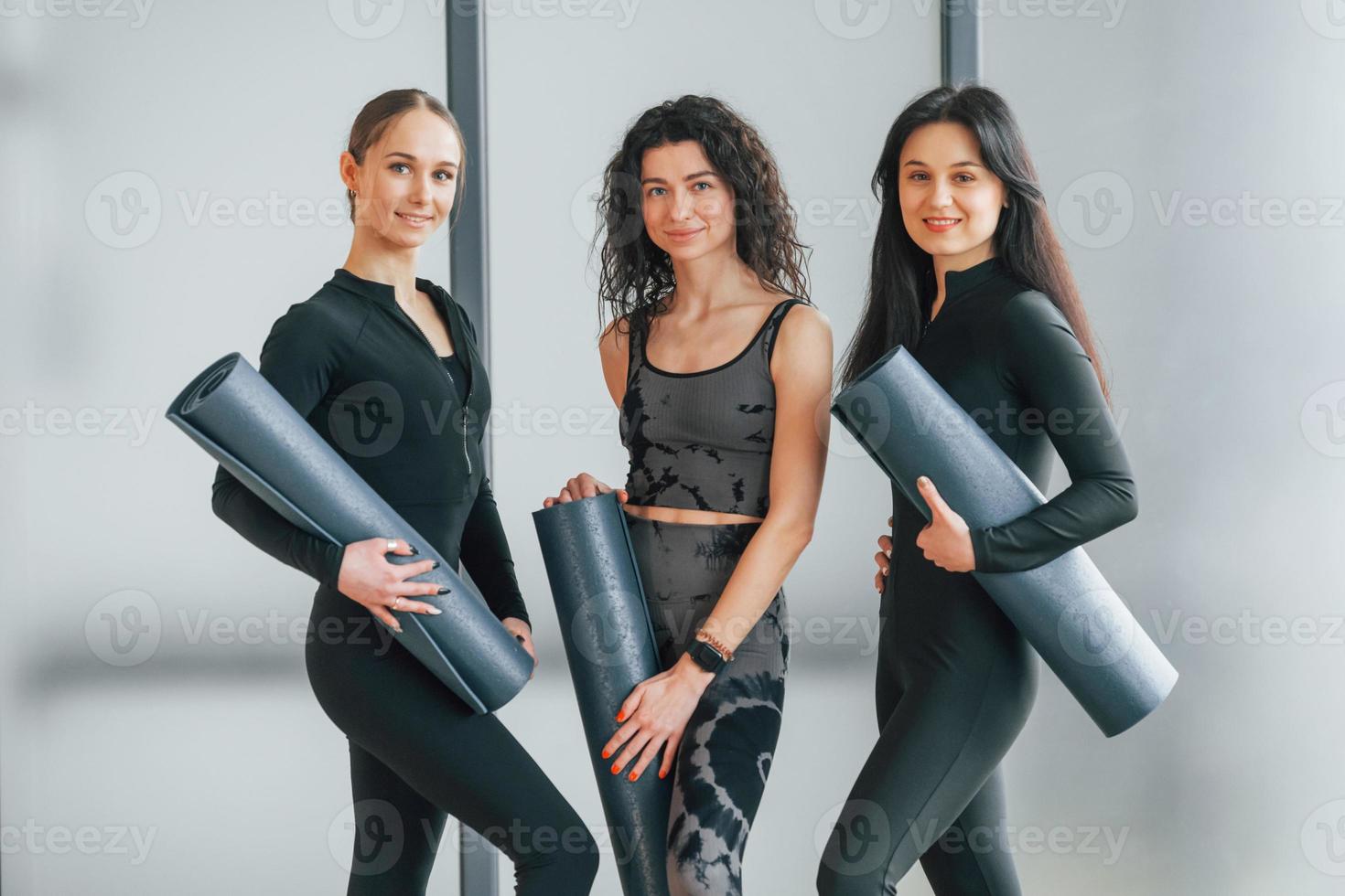 tenant des tapis de yoga. femmes en vêtements sportifs debout dans le centre de remise en forme photo