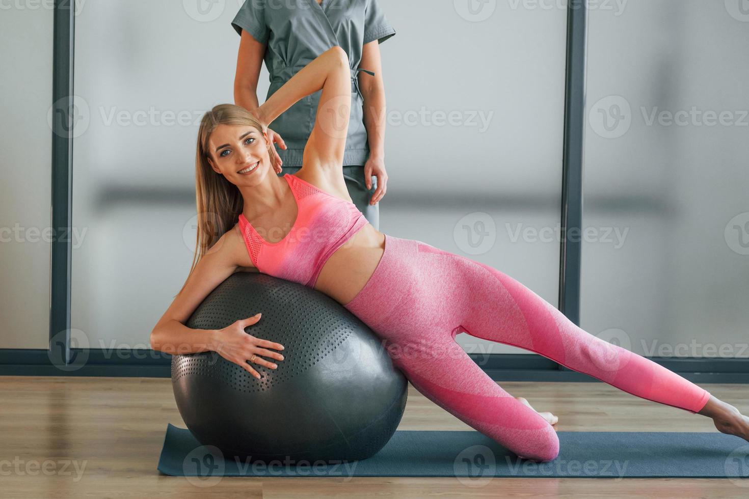 à l'aide d'un ballon de fitness. la femme est au centre de santé et reçoit l'aide d'un médecin photo