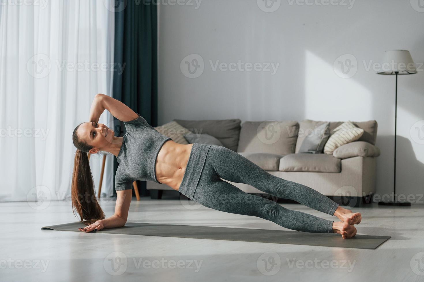 des exercices d'étirement. jeune femme au corps mince et en vêtements de yoga est à la maison photo