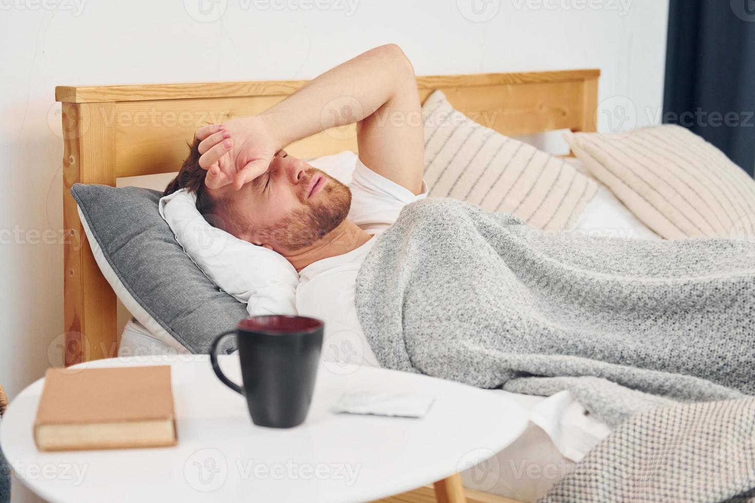 homme malade allongé sur le lit à la maison et se sent mal. conception de l'auto-isolement photo