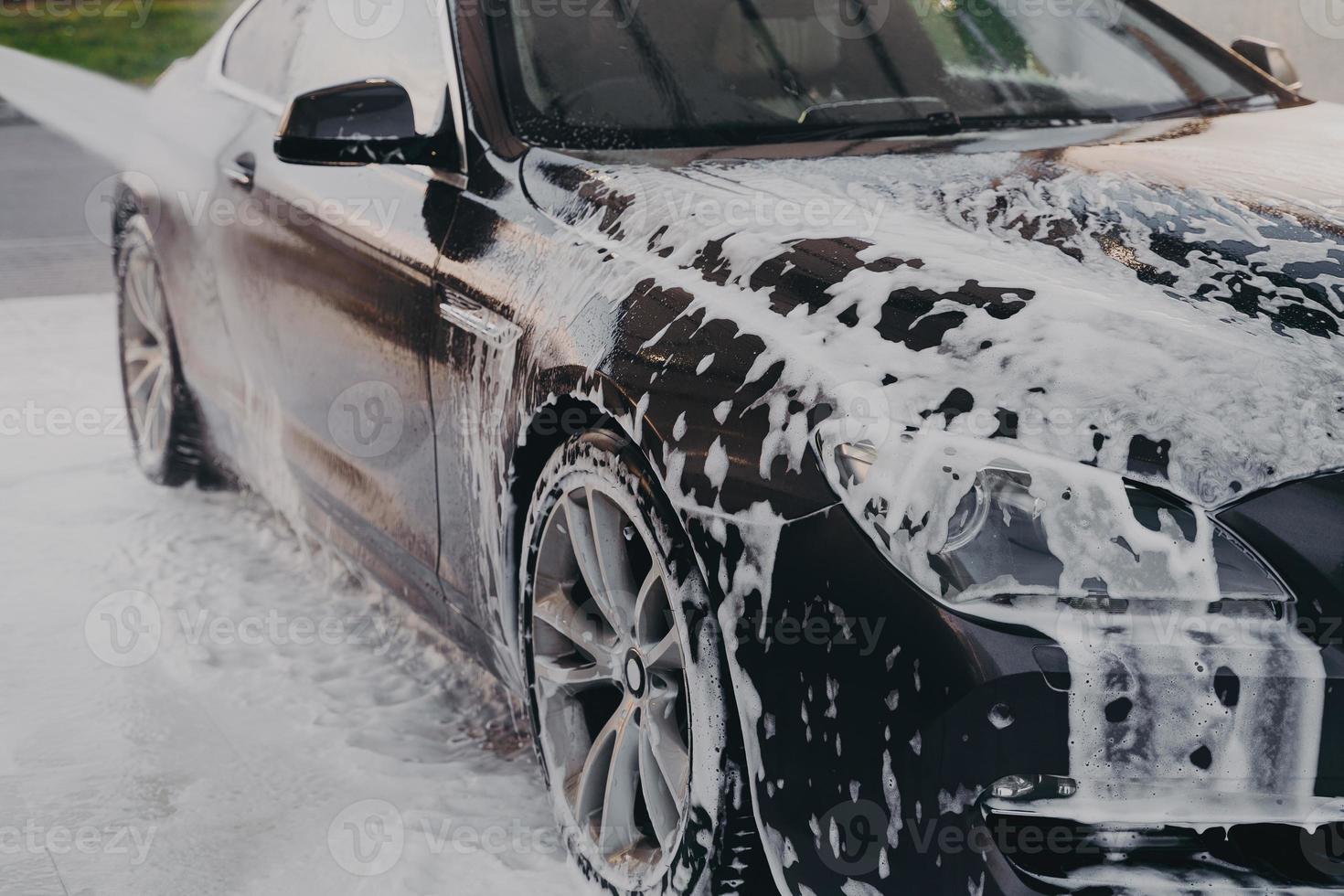 laver la mousse de savon blanc de la voiture avec un nettoyeur haute pression à l'extérieur photo