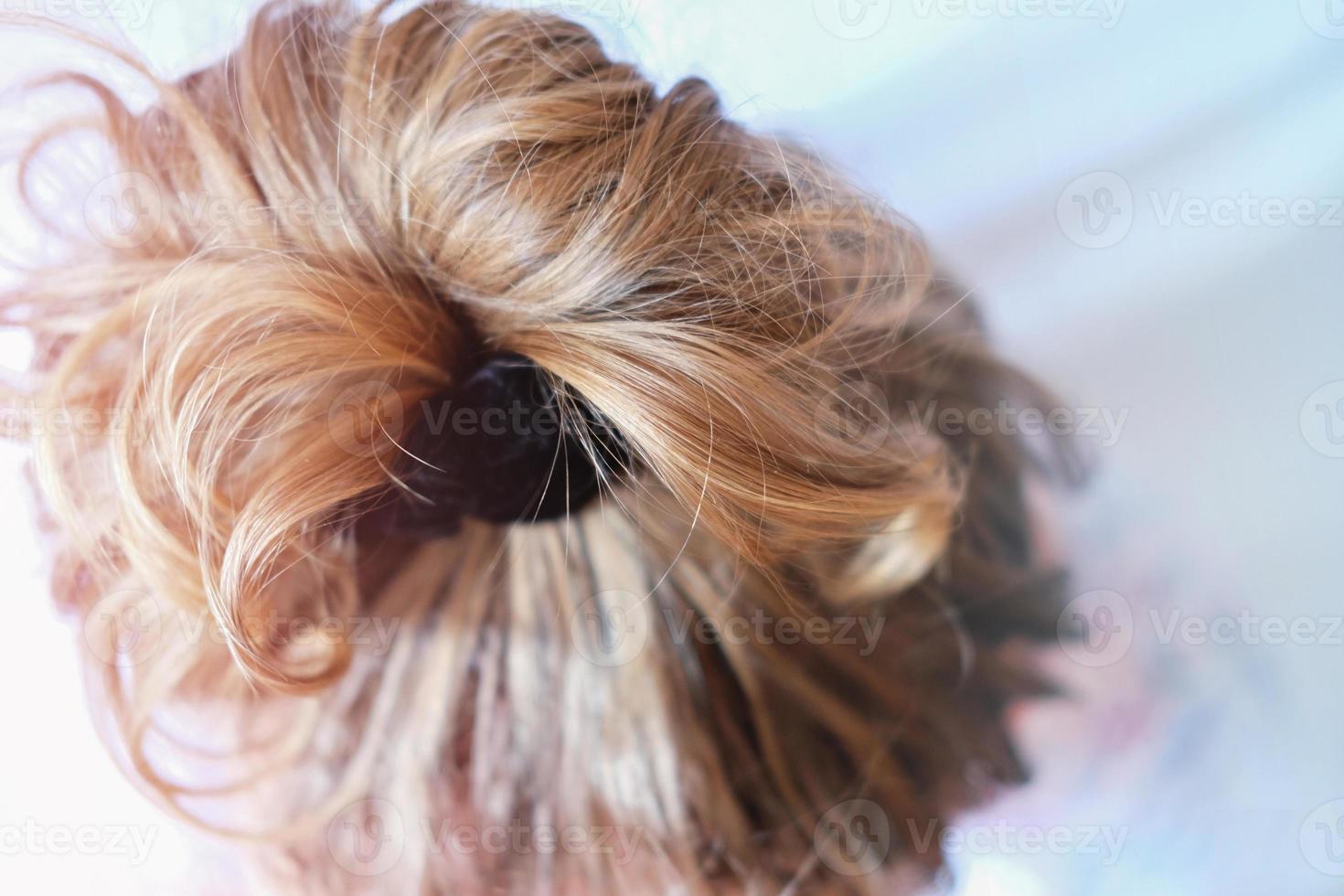 chignon désordonné sur la tête d'une femme blonde. cheveux légèrement bouclés. photo