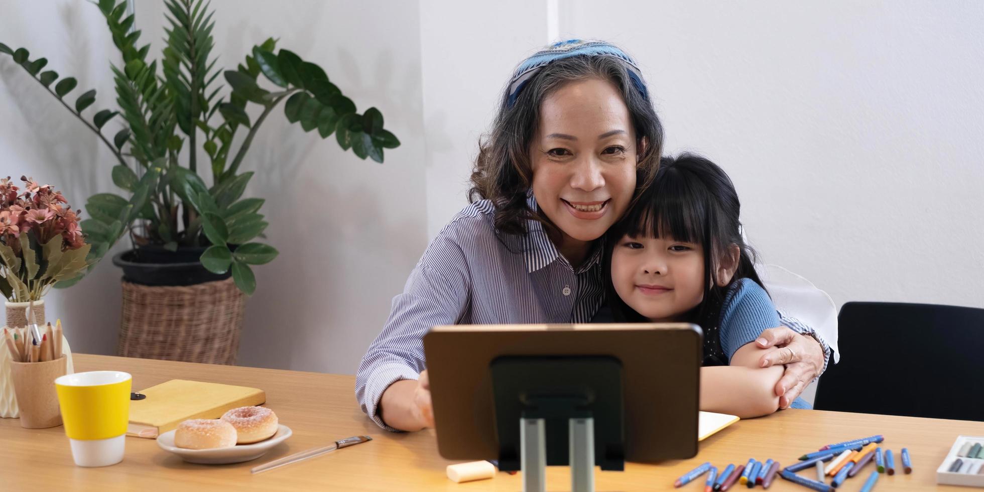 grand-mère senior souriante et petite-fille mignonne regardant ensemble des dessins animés sur un ordinateur portable, une grand-mère plus âgée heureuse jouant à un jeu ou faisant des achats en commandant en ligne avec une petite fille sur ordinateur photo