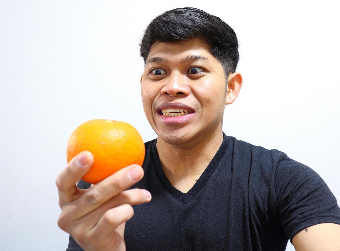 homme asiatique séduisant mangeant des oranges. isolé sur fond blanc photo