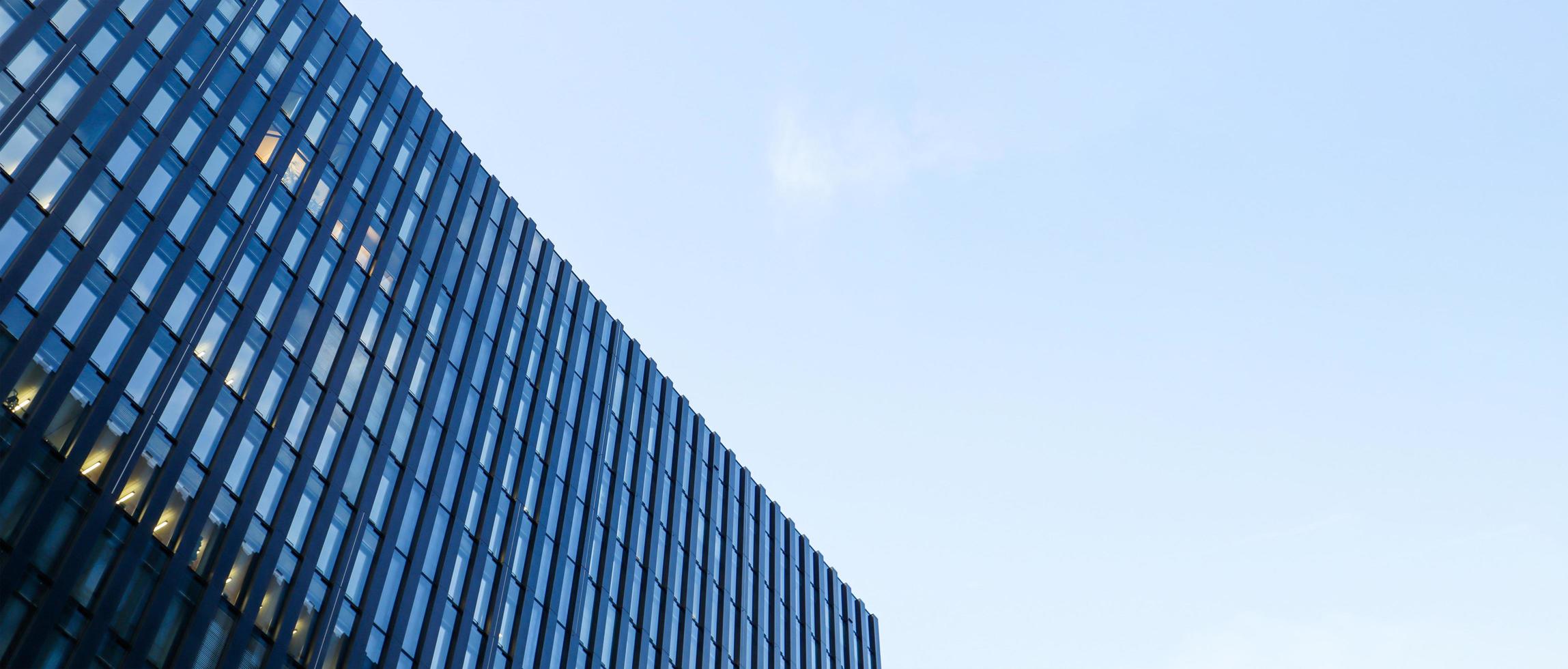 gratte-ciel moderne contre le ciel bleu. vue de dessous d'un gratte-ciel dans le quartier des affaires. vue en angle bas de la façade en verre d'un immeuble de bureaux. bannière avec espace de copie. photo