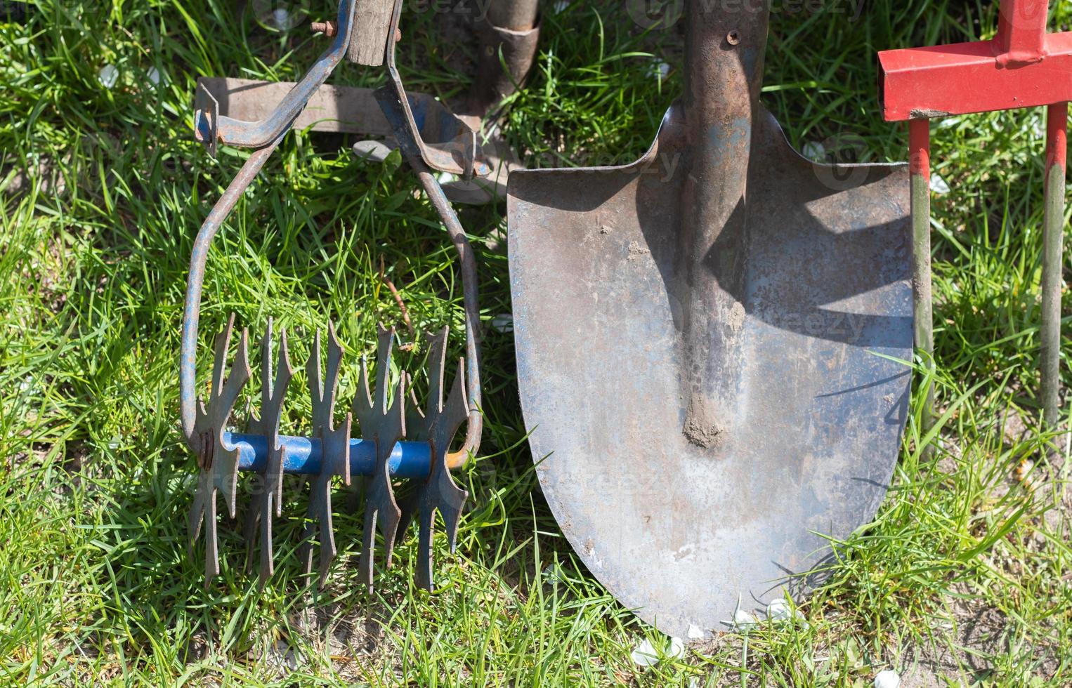 outils de jardinage. outils de jardin sur le fond d'un jardin dans l'herbe verte. outil de travail d'été. pelle, fourchette et levure chimique empilés dans le jardin à l'extérieur. le concept d'outils de jardinage. photo