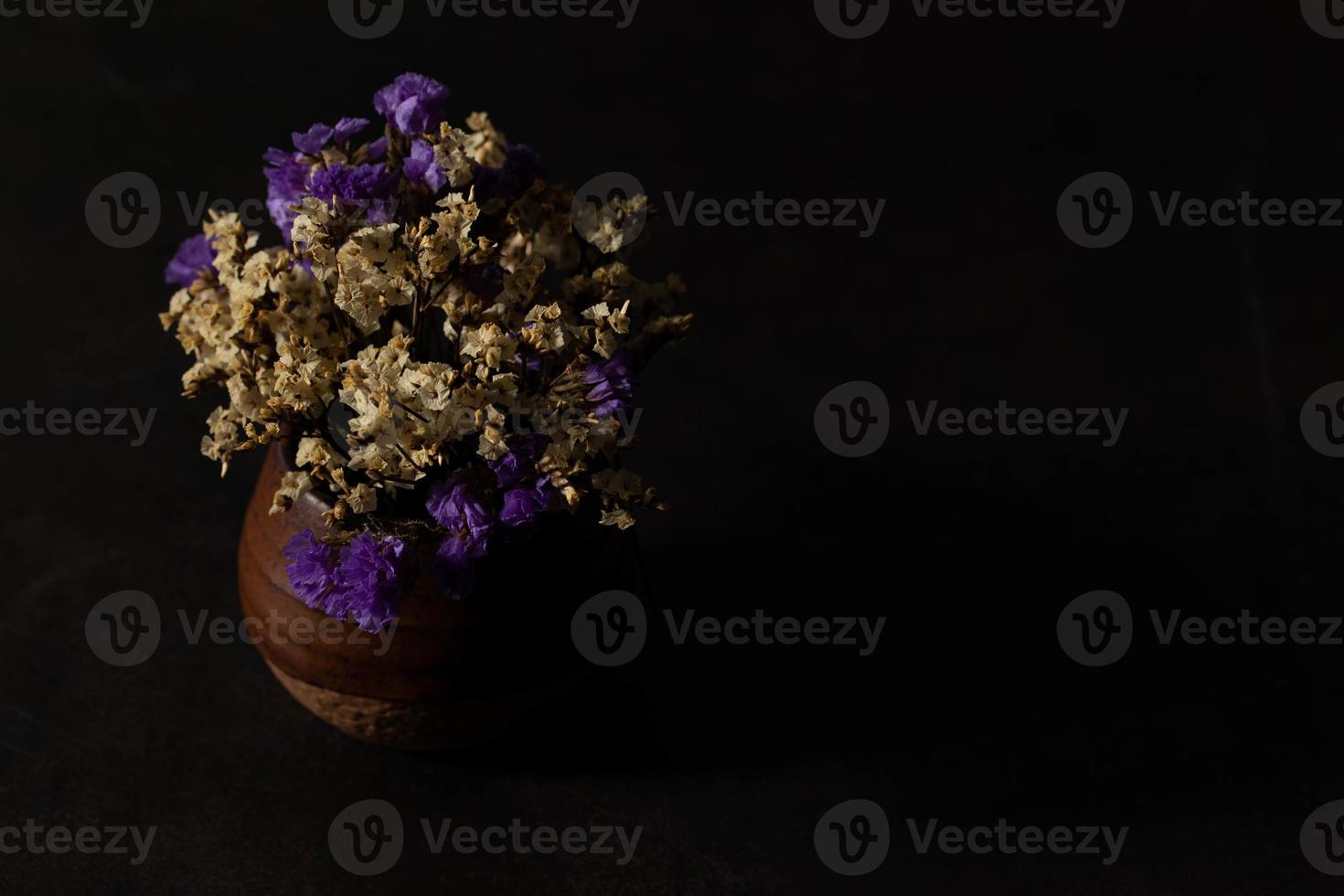 fleurs séchées dans un vase marron sur fond noir photo