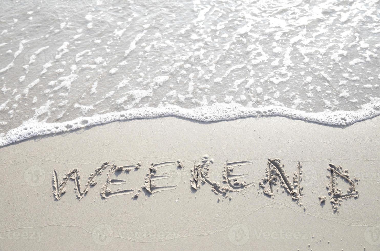 mot week-end écrit à la main dans le sable. gros plan sur la texture du sable de la plage en été. vacances, concept de vacances, photo