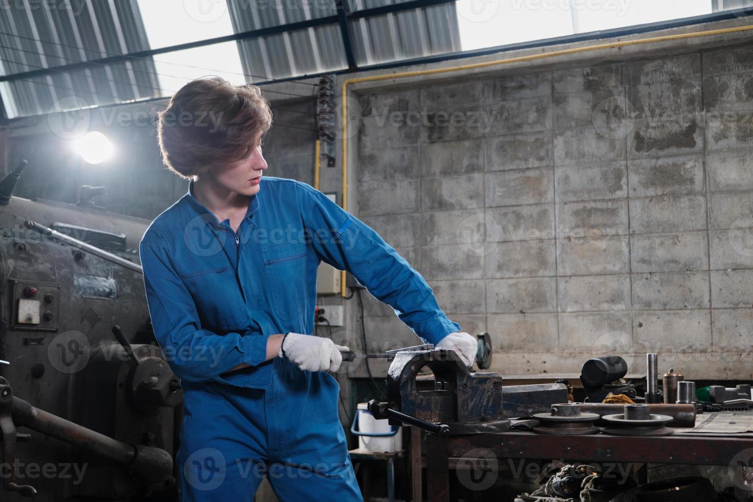 une jeune ingénieure professionnelle de l'industrie travaille dans un uniforme de sécurité avec des outils de précision pour la métallurgie, des tours mécaniques et un atelier de pièces de rechange dans l'usine de fabrication d'acier. photo